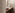 Badkamerhoek met travertin wandtegels en houten tafeltje met aardewerk schaal, vaasje en zeepbakje