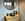 Betonlook wandtegels, ronde spiegel met zwarte lijst en houten badkamermeubel met matzwarte waskom en kraan